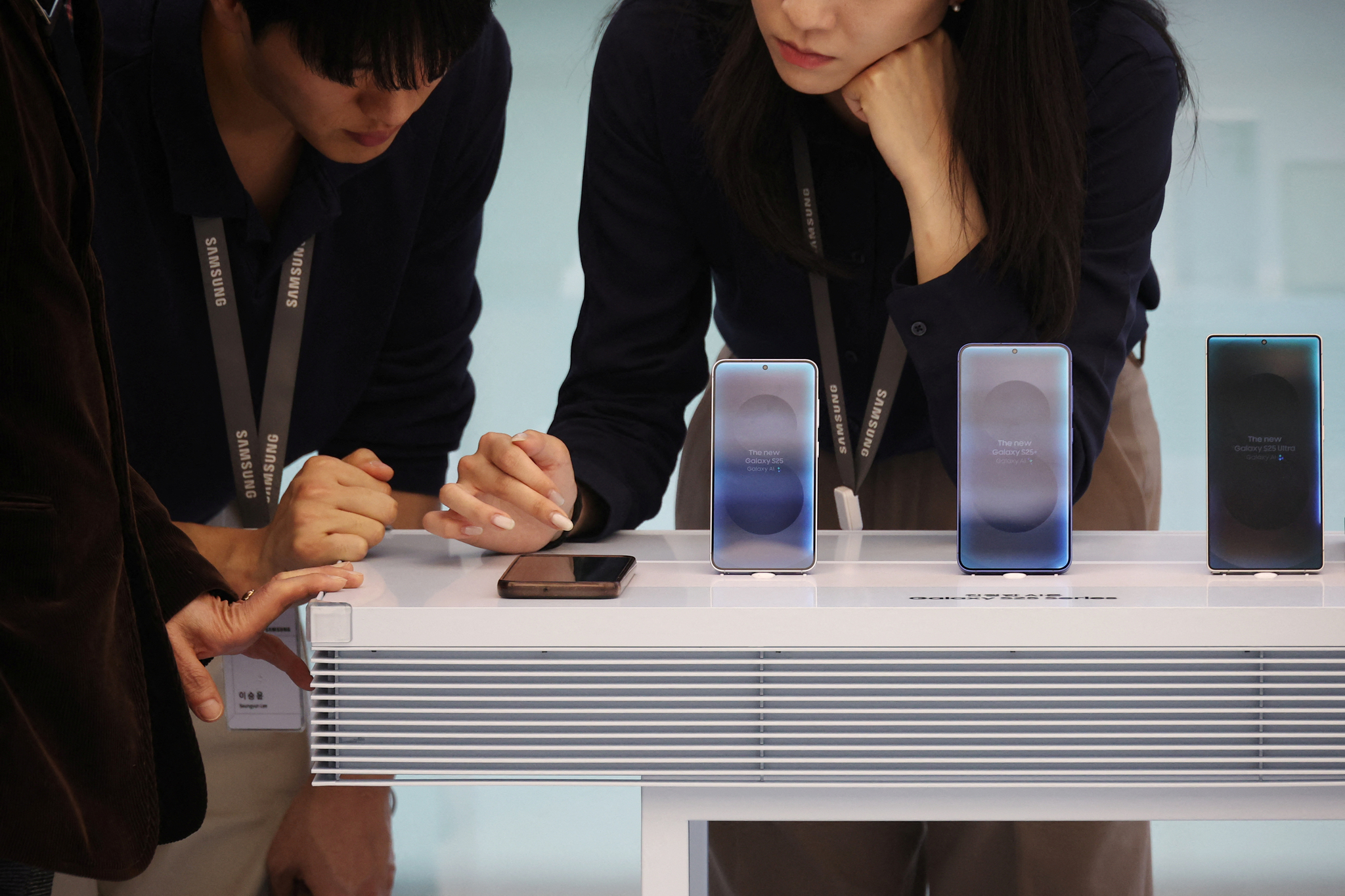 Samsung Electronics employees use the Galaxy S25 series at a Samsung store in Seoul on April 15. [REUTERS/YONHAP]