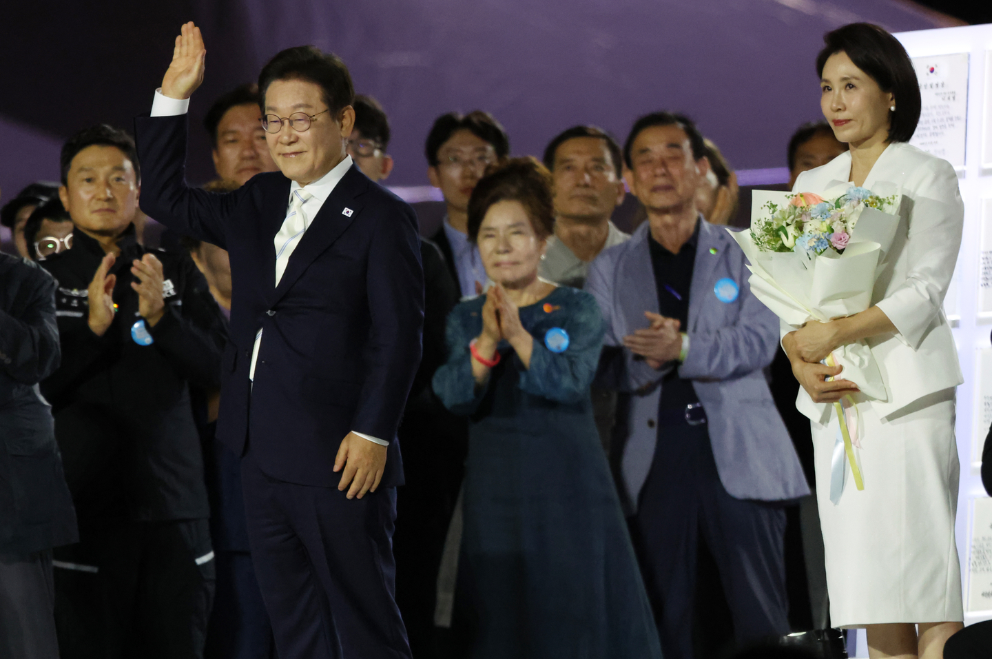 President Lee Jae Myung, left, waves his hands to people assembled in Gwanghwamun Square in Jongno District, central Seoul, during his ceremonial swearing-in at a nighttime event to mark the 80th anniversary of Korea's liberation from Japanese rule. His wife, first lady Kim Hye Kyung, stands to the right. [NEWS1] 