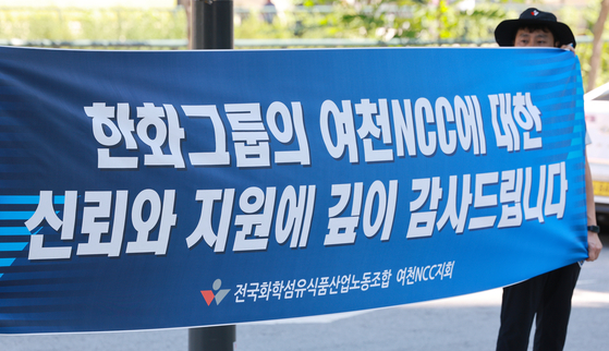 Members of the Yeochun NCC branch of the National Chemical, Fiber, and Food Industry Workers' Union hold up a banner with the message, ″We deeply appreciate Hanwha Group's trust and support for Yeochun NCC,″ in front of the Hanwha Building in Jung District, central Seoul, on Aug. 12. Yeochun NCC, a joint venture between Hanwha Group and DL Group, recently faced a crisis of bankruptcy due to the deteriorating petrochemical industry. While Hanwha Group is taking the position that it will prevent Yeochun NCC from defaulting even through additional support, Hanwha Solutions approved an additional loan of 150 billion won to the company at its board meeting in late July. [YONHAP]