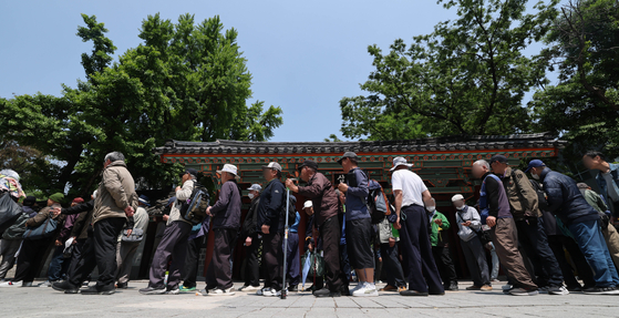 Older people wait in line to receive meals at a soup kitchen in Tapgol Park in Jongno District, central Seoul, on May 12. [NEWS1] 