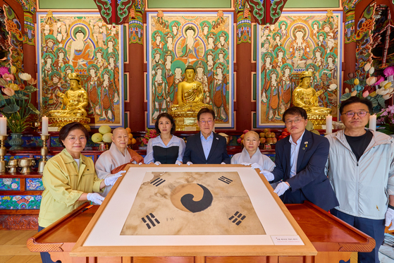 President Lee Jae Myung and first lady Kim Hea Kyung hold up a Taegeukgi, a Korean flag, discovered during the restoration process of Jingwansa Temple in 2009 during their visit to the temple in Eunpyeong District, northern Seoul on Aug. 17. [NEWS1]