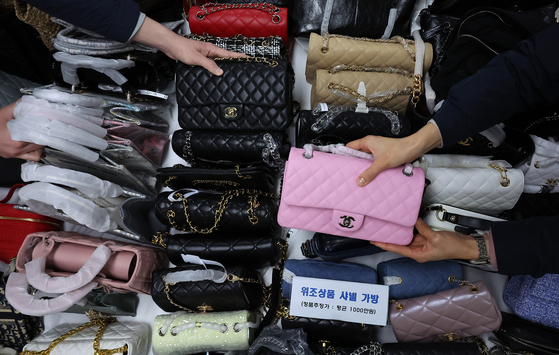 Employees from the Seoul Metropolitan Government’s Special Police Bureau for Citizens' Livelihood & Safety organizes counterfeit bags and other confiscated items at the Namsan annex of Seoul City Hall in Jung District, central Seoul, on Feb. 20. [NEWS1] 