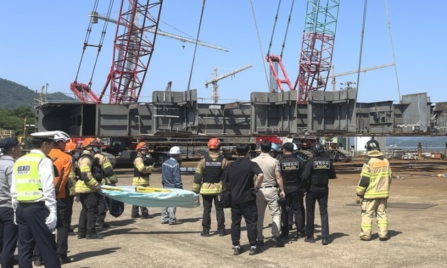 Firefighters at the scene wait for a structure to be lifted by crane to carry out rescue operations. In May 2024, two workers at a shipbuilding company in South Gyeongsang died after being crushed under a ship structure. [GYEONGSANGNAM-DO FIRE DEPARTMENT]