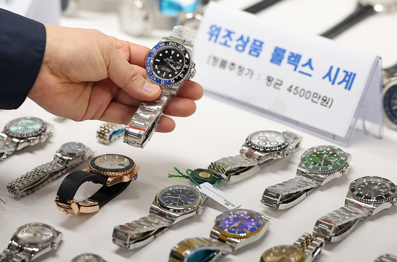 An employee from the Seoul Metropolitan Government’s Special Police Bureau for Citizens' Livelihood & Safety holds up a confiscated counterfeit watch at the Namsan annex of Seoul City Hall in Jung District, central Seoul, on Feb. 20. [NEWS1]