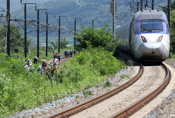 A Mugunghwa train hit seven workers on the tracks in Cheongdo County, North Gyeongsang, on Aug. 19. As police, firefighters, and Korail officials investigate the scene, a train is seen passing slowly on the right. [NEWS1]