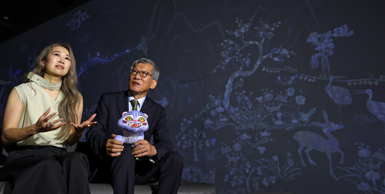Maggie Kang, left, writer and director of Netflix film ″KPop Demon Hunters,″ and Yu Hong-jun, director of the National Museum of Korea, look at digital art at the museum in Yongsan District, central Seoul, on Aug. 21. [YONHAP]