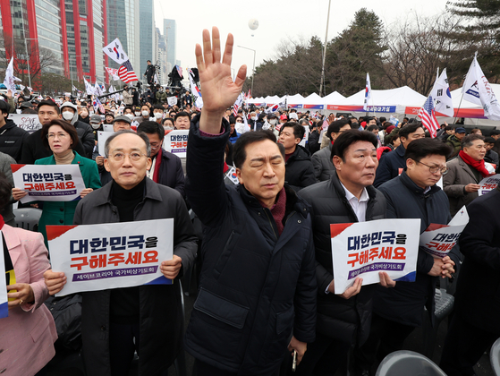 Conservative People Power Party (PPP) Rep. Kim Gi-hyeon, center, raises his hands into the sky in prayer at a rally in Yeouido, western Seoul, on March 1. PPP Rep. Choo Kyung-ho, left, holds up a placard that says ″Please Save Korea.″ [NEWS1]