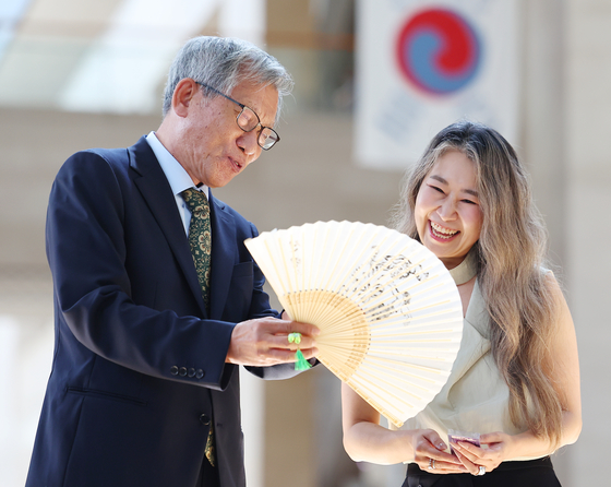 Yu Hong-jun, left, director of the National Museum of Korea, gifts a fan to Maggie Kang, writer and director of Netflix film ″KPop Demon Hunters,″ at the museum in Yongsan District, central Seoul, on Aug. 21. [YONHAP] 