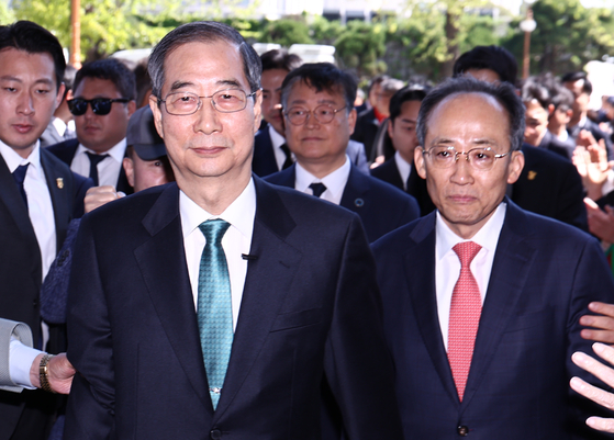 Former Prime Minister Han Duck-soo, left, and conservative People Power Party Rep. Choo Kyung-ho enter the National Assembly building to declare Han's presidential candidacy on May 2 in western Seoul. [NEWS1]