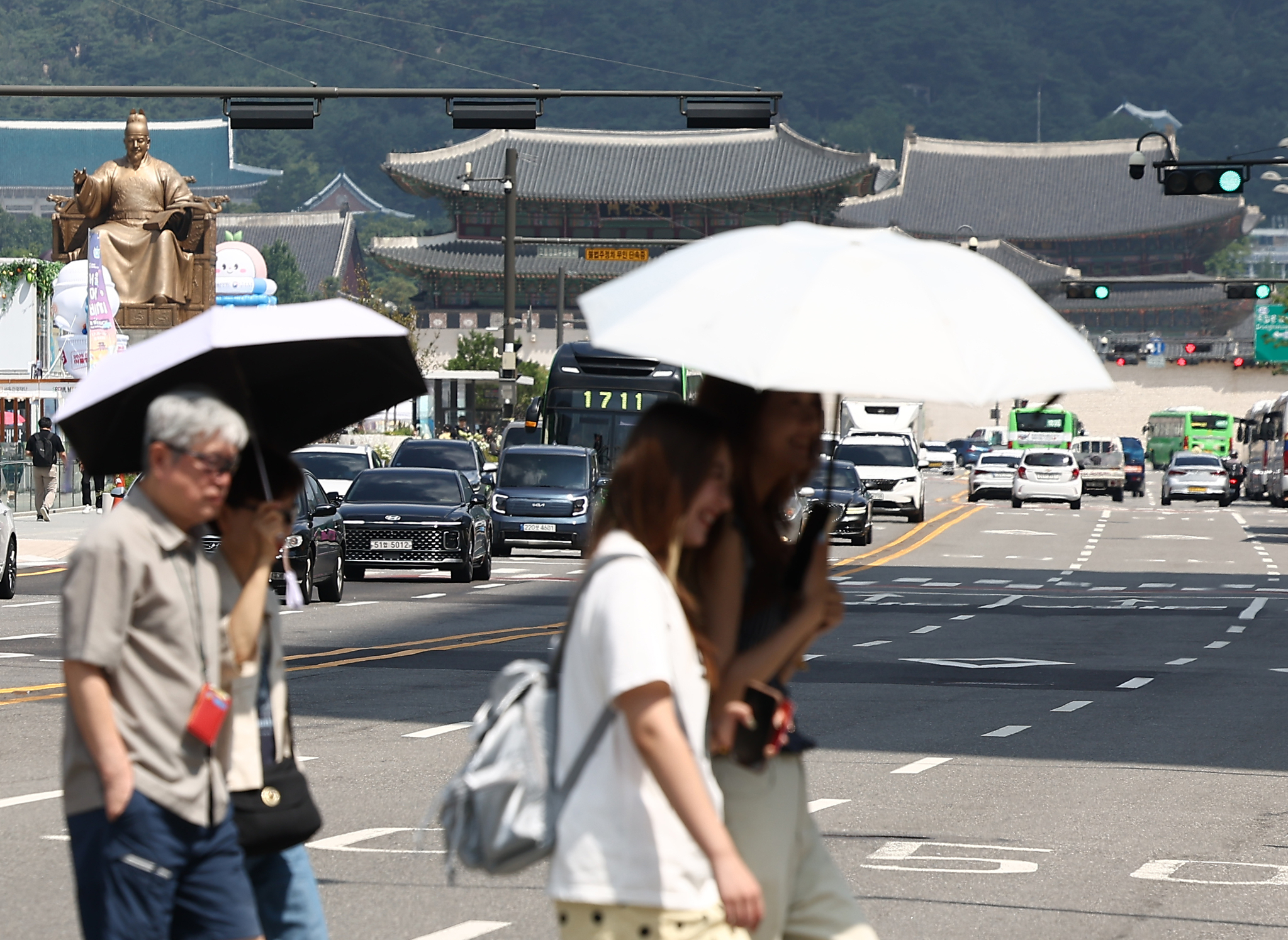 Pedestrians walk with parasols past Gwanghwamun Square in central Seoul on Aug. 5. [YONHAP]