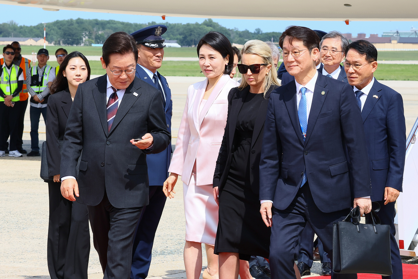 President Lee Jae Myung, left, and first lady Kim Hea Kyung, second from left, are greeted by U.S. officials as they arrive at Joint Base Andrews in Maryland on Aug. 24 from Tokyo to begin a three-day trip to the United States for a bilateral summit with U.S. President Donald Trump. [JOINT PRESS CORPS]