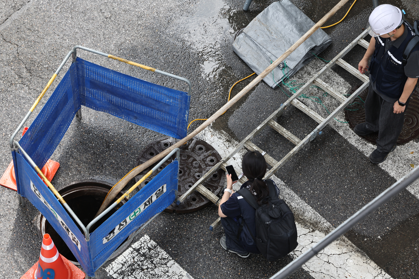 First responders and firefighters conduct rescue operations for a worker who was swept into a manhole at a street in Yeomchang-dong, Gangseo District, western Seoul on Aug. 25. [YONHAP]