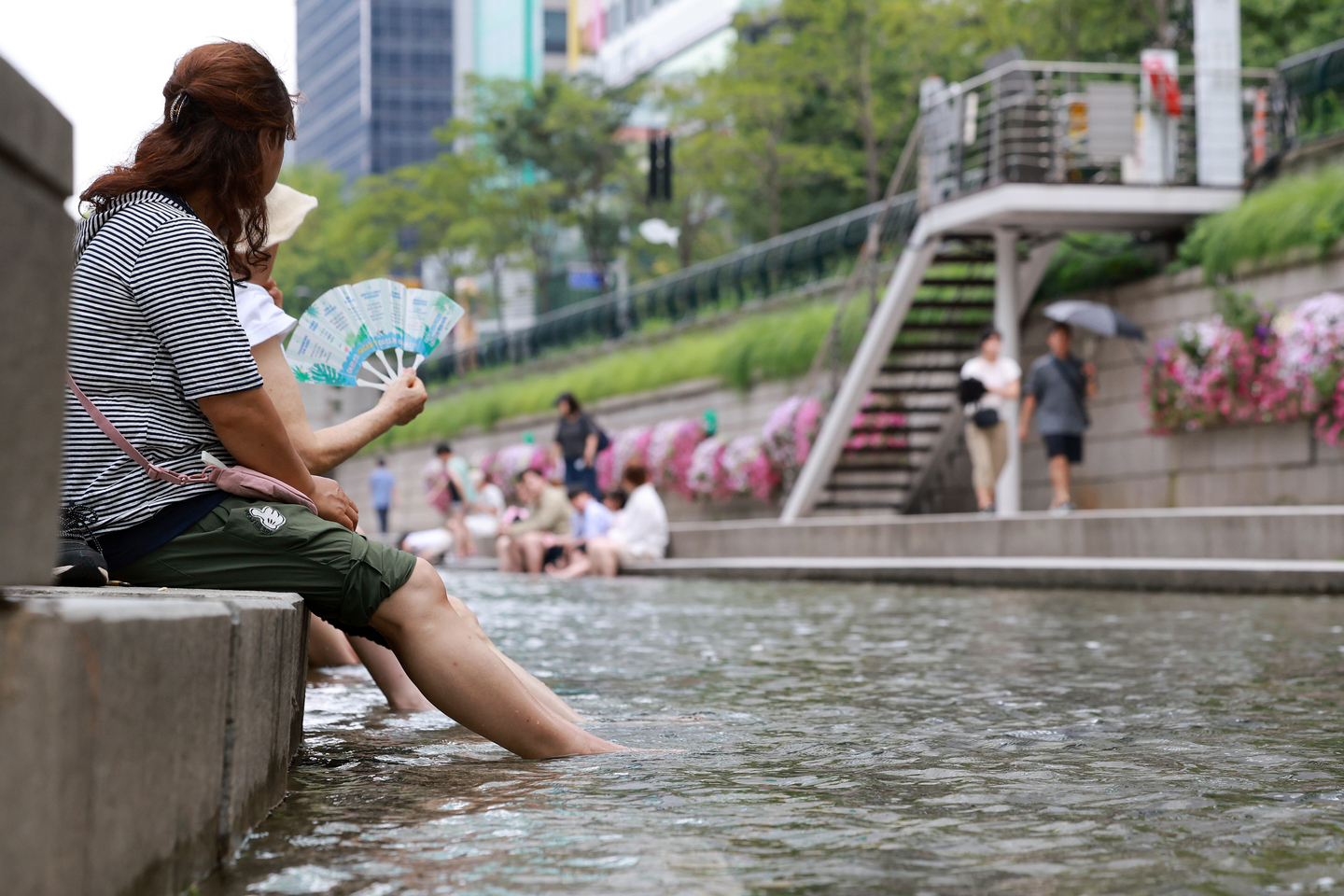 People cool off by dipping their feet in the Cheonggye Stream in central Seoul on Aug. 1. [YONHAP] 