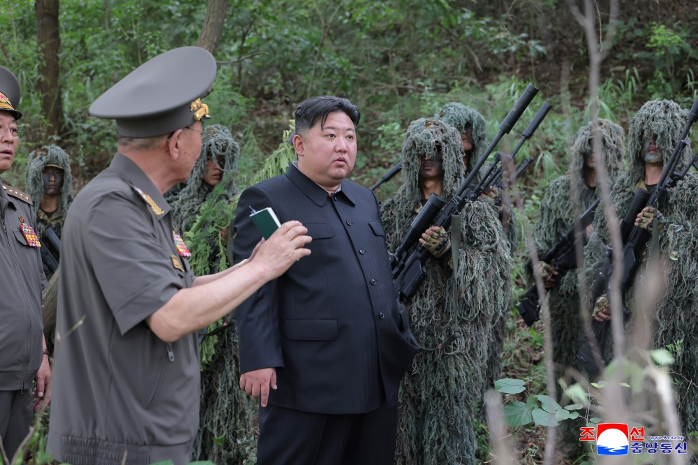 North Korean leader Kim Jong-un, center, speaks to officials during his visit to a special operations training base on Aug. 27. [KCNA]