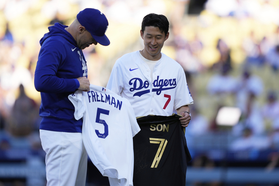 Los Angeles FC forward Son Heung-min, right, trades jerseys with Los Angeles Dodgers first baseman Freddie Freeman before the MLB game between the Los Angeles Dodgers and the Cincinnati Reds on Aug. 27 in Los Angeles. [AP/YONHAP]