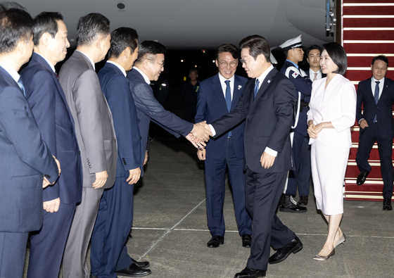 President Lee Jae Myung, second from right, and first lady Kim Hea Kyung, right, greet ministers and aides after returning on the presidential jet from the United States, at Seoul Air Base in Seongnam, Gyeonggi, on Aug. 28. [JOINT PRESS CORPS]