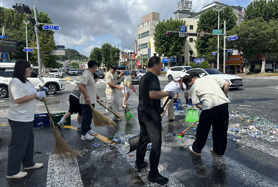 Daejeon Sports Council employees clean up beer bottles spilled from a delivery truck at the Chungmu-ro intersection in Daeheung-dong, Jung District, Daejeon, at around 10:20 a.m. on Aug. 29. [NEWS1]