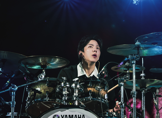 DAY6 member Dowoon plays drum during its 10th anniversary tour ″The Decade″ at the Goyang Stadium in Goyang, Gyeonggi, on Sunday. [JYP ENTERTAINMENT]