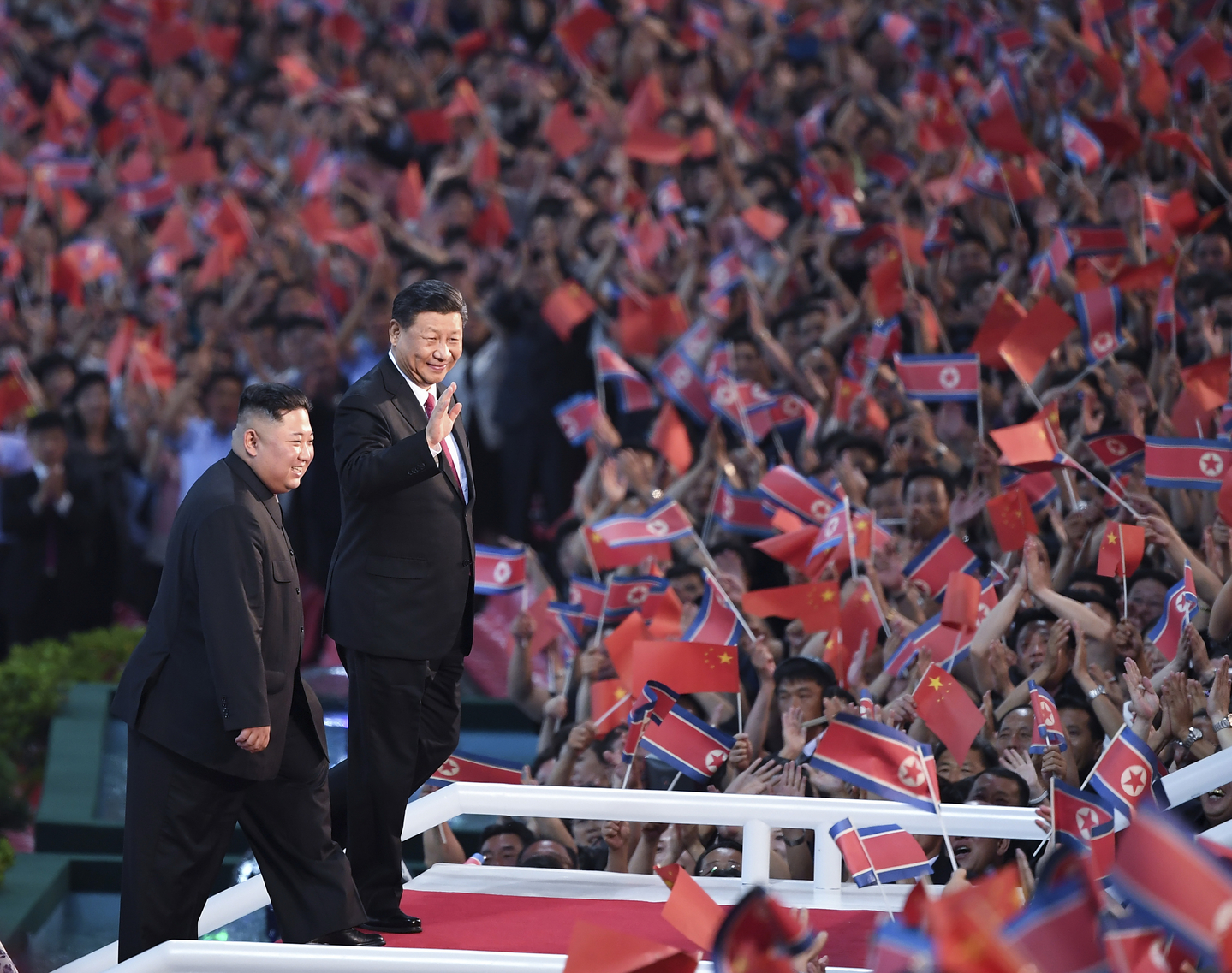Spectators wave Chinese and North Korean flags as North Korean leader Kim Jong-un, left, and visiting Chinese President Xi Jinping attend a mass gymnastic performance at the May Day Stadium in Pyongyang on June 20, 2019. [XINHUA/YONHAP]