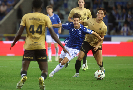 Oh Hyeon-gyu of KRC Genk, right, and Leo Bengtsson of Poznan, center, is seen in action during the UEFA Europa League play-offs between KRC Genk and Lech Poznan in Genk, Belgium, on Aug. 28. [EPA/YONHAP]