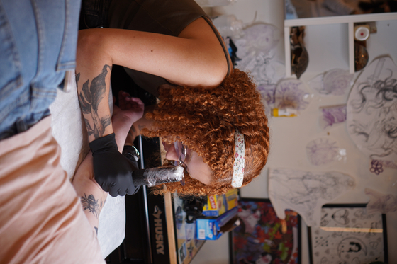 Sun Child gives a tattoo to her client in the United States in April last year. [SUN CHILD]