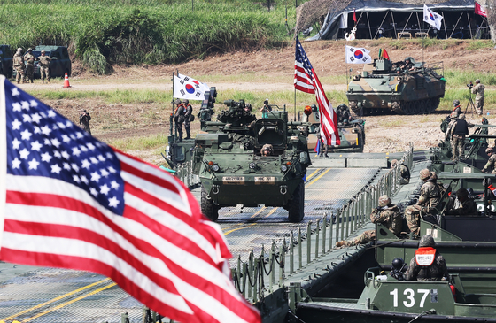 A U.S. Stryker armored vehicle and a Korean K200 armored vehicle cross a pontoon bridge over the Namhan River during a combined arms river-crossing drill in Yeoju, Gyeonggi on Aug. 27. [YONHAP]