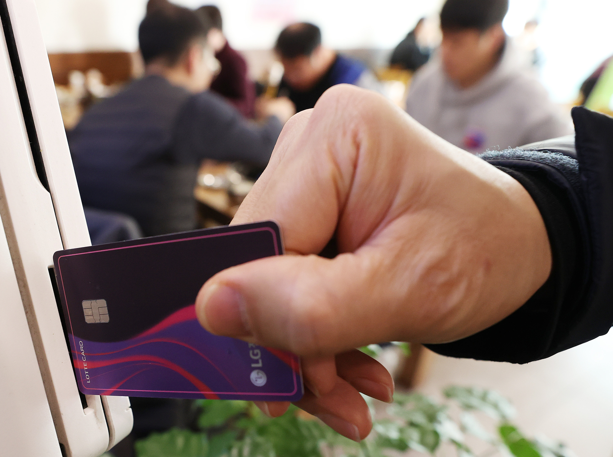 A credit card being swiped at a restaurant in Seoul in December 2021. [YONHAP] 