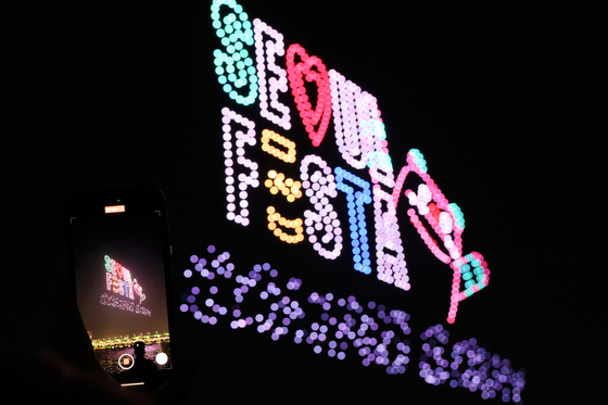 A visitor takes a photo of drones making the Seoul Festa logo at Jamsil Hangang Park in Songpa District, southern Seoul, in April 2024. [YONHAP] 