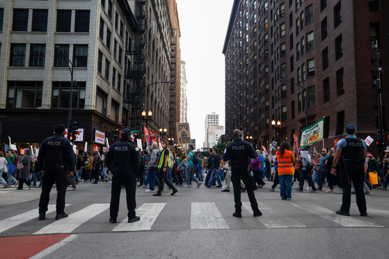 Police officers watch as people participate in a demonstration against the planned deployment of National Guard troops in Chicago on Sept. 6. [AFP/YONHAP]