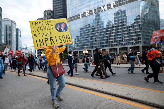 People hold anti-Trump signs as they march past Trump International Hotel & Tower during a demonstration against the planned deployment of National Guard troops in Chicago on Sept. 6. [AFP/YONHAP]