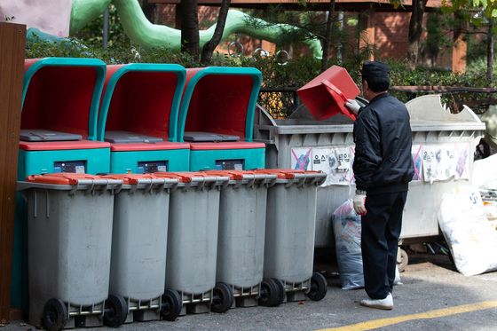 An apartment security guard is seen organizing recycling bins on the grounds of an apartment complex in Seoul on Oct. 21, 2021. [NEWS1]