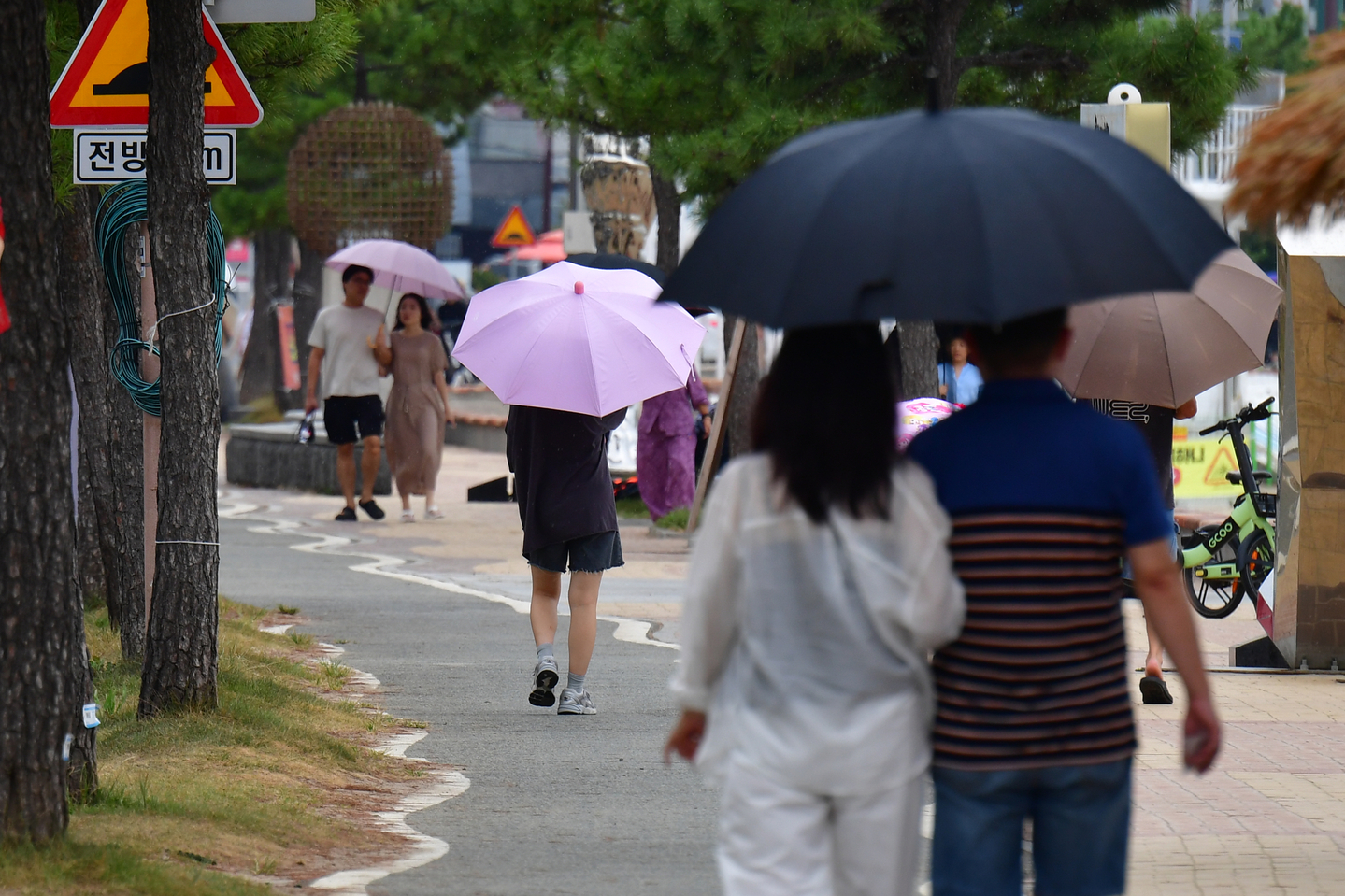 Pedestrians walk along the coastal road with umbrellas at Yeongildae Beach in Buk District, Pohang, North Gyeongsang, on Sept. 7. [NEWS1]