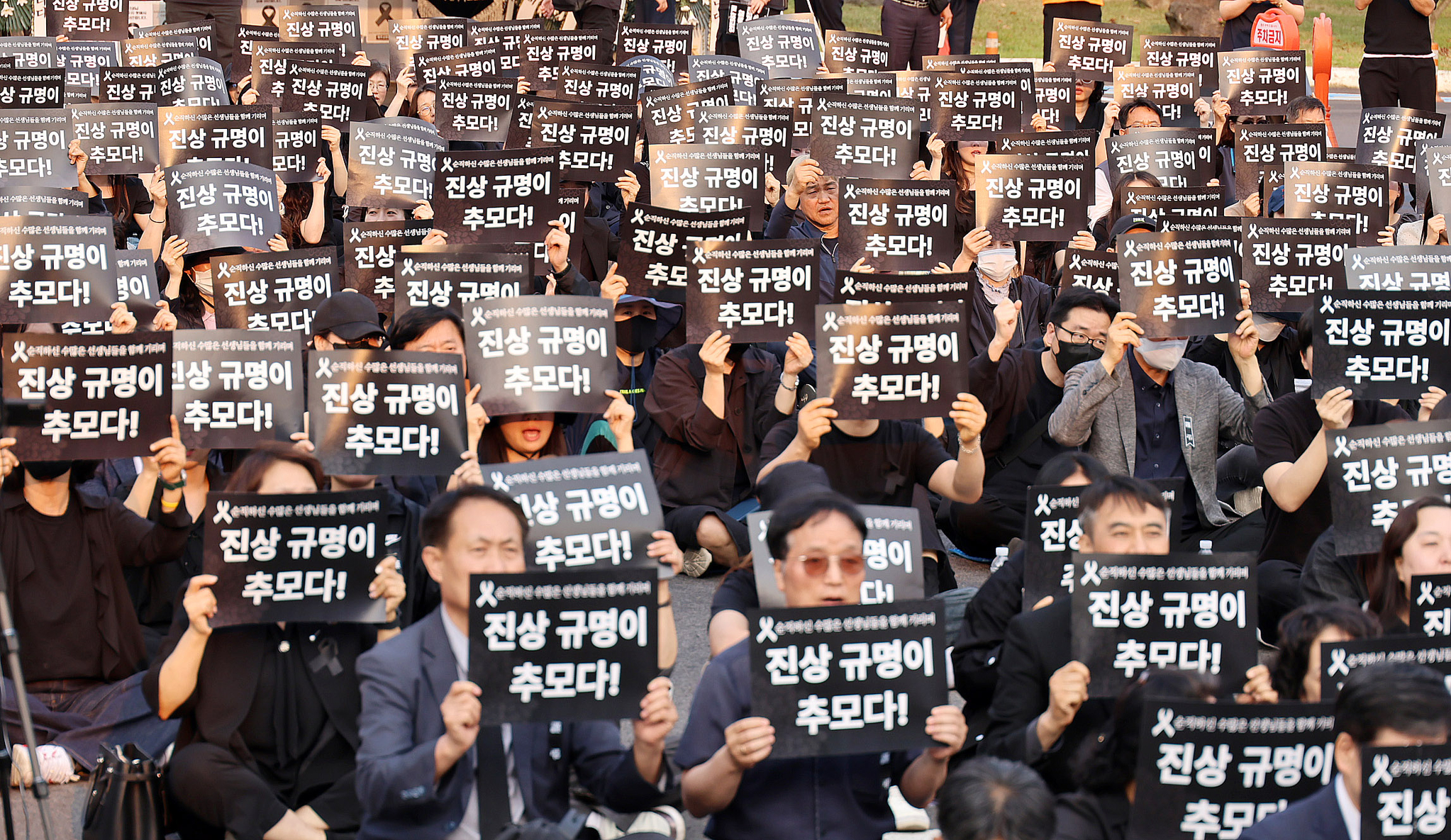 Participants hold up placards reading “Truth-finding is remembrance” and chant slogans during a memorial event for a middle school teacher in Jeju on the front lawn of the Jeju Provincial Office of Education on May 30. [YONHAP]