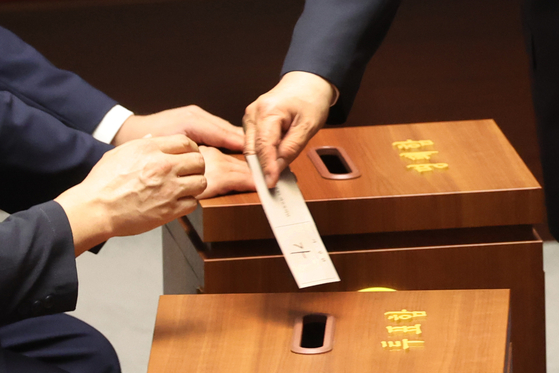 Rep. Kweon Seong-dong of the People Power Party, who faces charges of accepting political funds from the Unification Church, casts his vote on a motion for his arrest during a plenary session at the National Assembly in western Seoul on Sept. 11. He previously stated he would waive his parliamentary immunity and placed a ballot marked “yes” into the box. [[YONHAP]