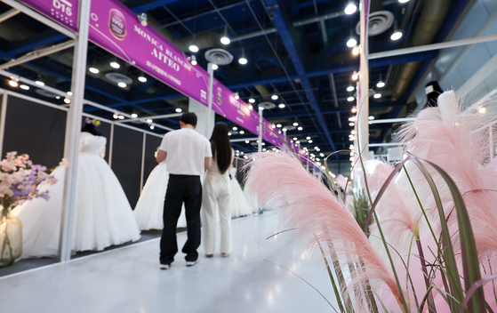 Engaged couples look at displayed dresses at a wedding fair at Coex in southern Seoul on July 6. [NEWS1] 