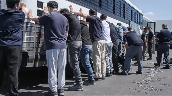 Immigration and customs agents restrain workers who were apprehended at a battery plant construction site on charges of violating U.S. immigration rules in Savannah, Georgia. More than 300 Korean nationals were reported to be captured during the raid. [SCREEN CAPTURE]