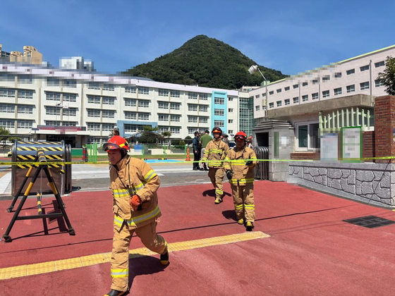 Firefighters search a high school in Busan after two schools reported receiving a bomb threat via fax on Sept. 2. [BUSAN METROPOLITAN POLICE AGENCY]