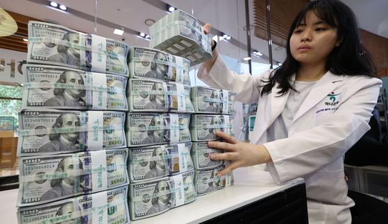 A banker checks dollar bills at Hana Bank's Counterfeit Notes Response Center in Seoul on July 1. [YONHAP]