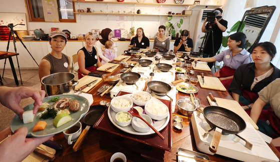 International visitors take part in a hands-on cooking class at Omi Culinary Lab in a "Seoul Table" culinary class in Jegi-dong, Dongdaemun District, eastern Seoul, on Sept. 15. The program, hosted by the Seoul Metropolitan Government, offers foreigners a chance to shop for ingredients at traditional markets and prepare Korean dishes alongside star chefs. [YONHAP] 