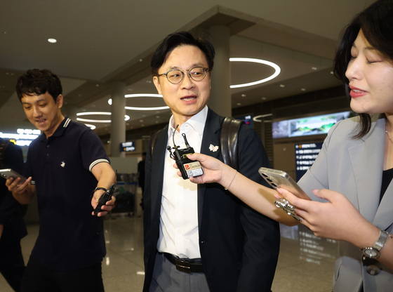 Industry Minister Kim Jung-kwan, center, answers questions from reporters upon arrival at Incheon International Airport on Sept. 14. [YONHAP]