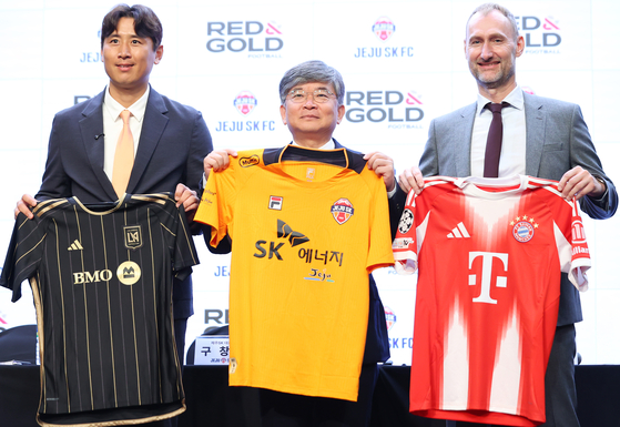 Officials for the partnership signing ceremony between Jeju SK FC and Red & Gold Football, a joint venture between FC Bayern Munich and Los Angeles Football Club, pose with the shirts of the three clubs at Stanford Hotel in Seoul on Sept. 15. From left: Koo Ja-cheol, youth adviser for Jeju SK FC, Ku Chang-yong, CEO of Jeju SK FC, and Jochen Sauer, Red & Gold Football's managing director. [YONHAP]