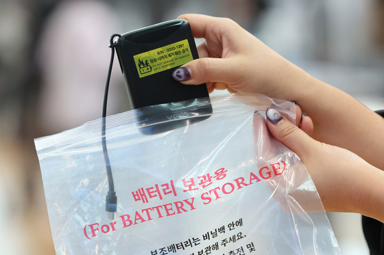An airline staff member attaches a sticker to a portable battery before placing it in a plastic bag at a Korean Air check-in counter at Terminal 2 of Incheon International Airport on March 1, as the Ministry of Land, Infrastructure and Transport begins enforcing new safety standards for portable batteries and e-cigarettes. [YONHAP]