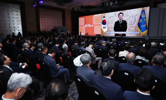 Attendees of the JoongAng Ilbo’s 60th anniversary ceremony watch President Lee Jae Myung’s congratulatory speech at Lotte Hotel in Jung District, central Seoul, on Sept. 17. [JANG JIN-YOUNG] 