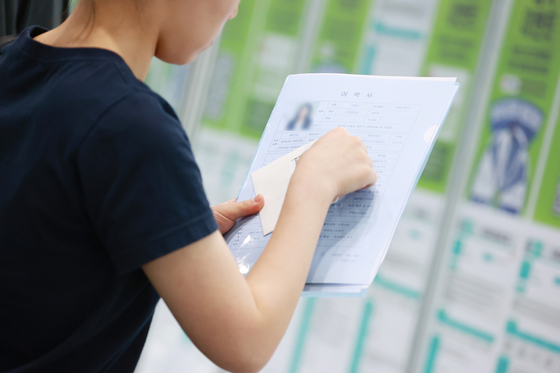 A job seeker looks around employment notices with a resume in hand at a job fair held at Coex in Gangnam District, southern Seoul on June 5. [YONHAP]