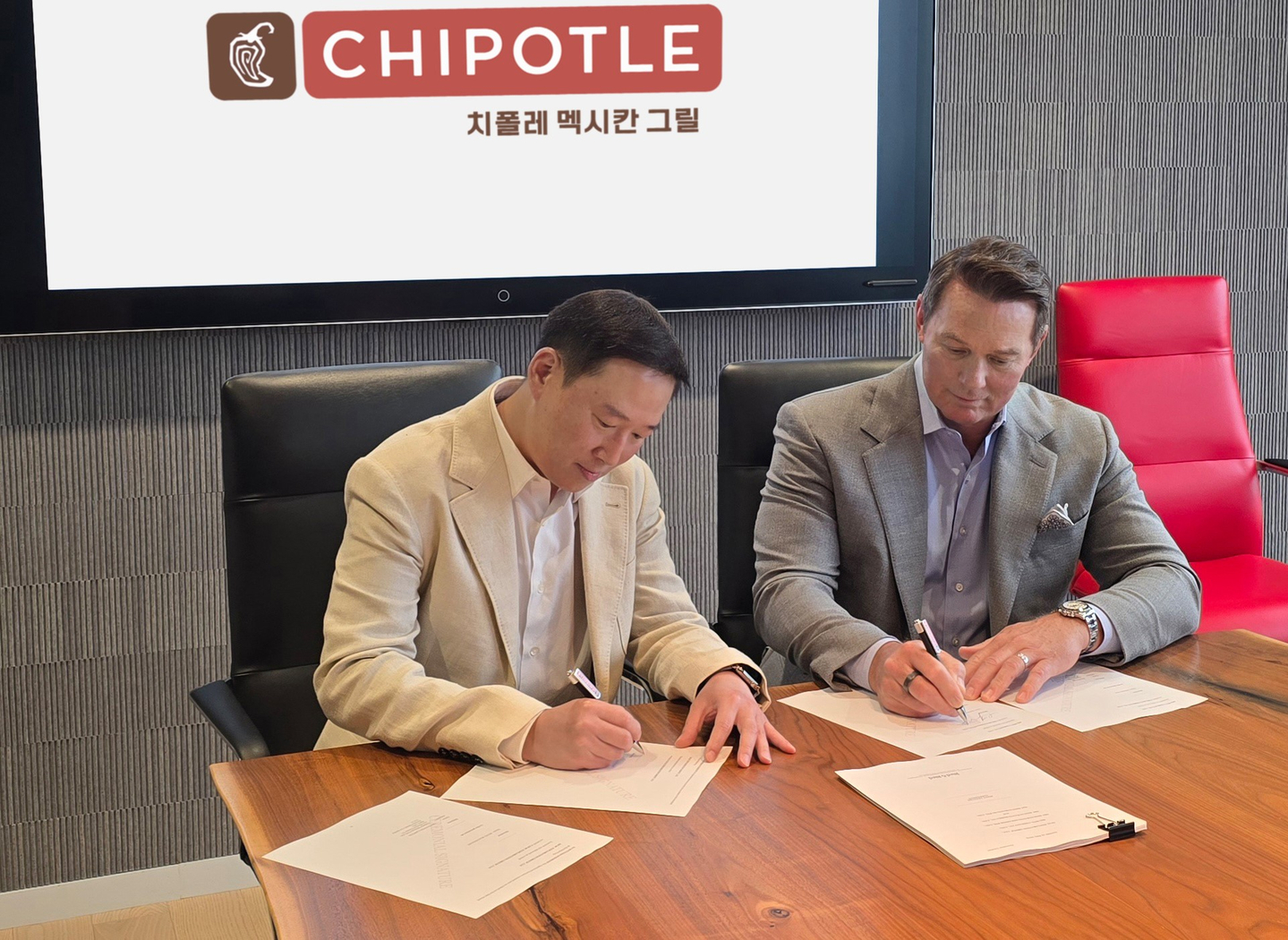 Scott Boatwright, right, CEO of Chipotle Mexican Grill, and Hur Hee-soo, vice president of SPC Group, sign an agreement to establish a joint venture to operate Chipotle's business in Korea and Singapore. [SPC GROUP]