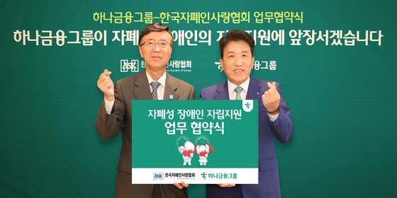Hana Financial Group CEO Ham Young-joo, right, poses for photos with Autism Society of Korea President Kim Yong-jik, after signing an agreement to help support people with autism in Korea on Sept. 19 at the Hana Financial Group's Myeongdong office in central Seoul. [HANA FINANCIAL GROUP]