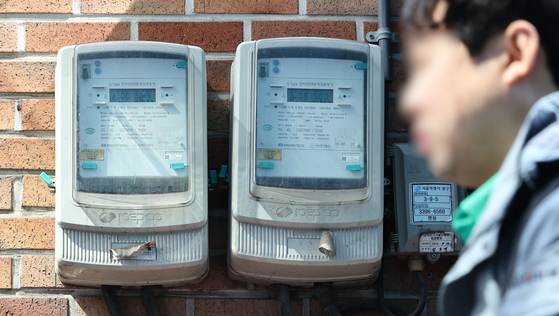 A pedestrian walks by an electric meter in Seoul on March 21. [YONHAP]
