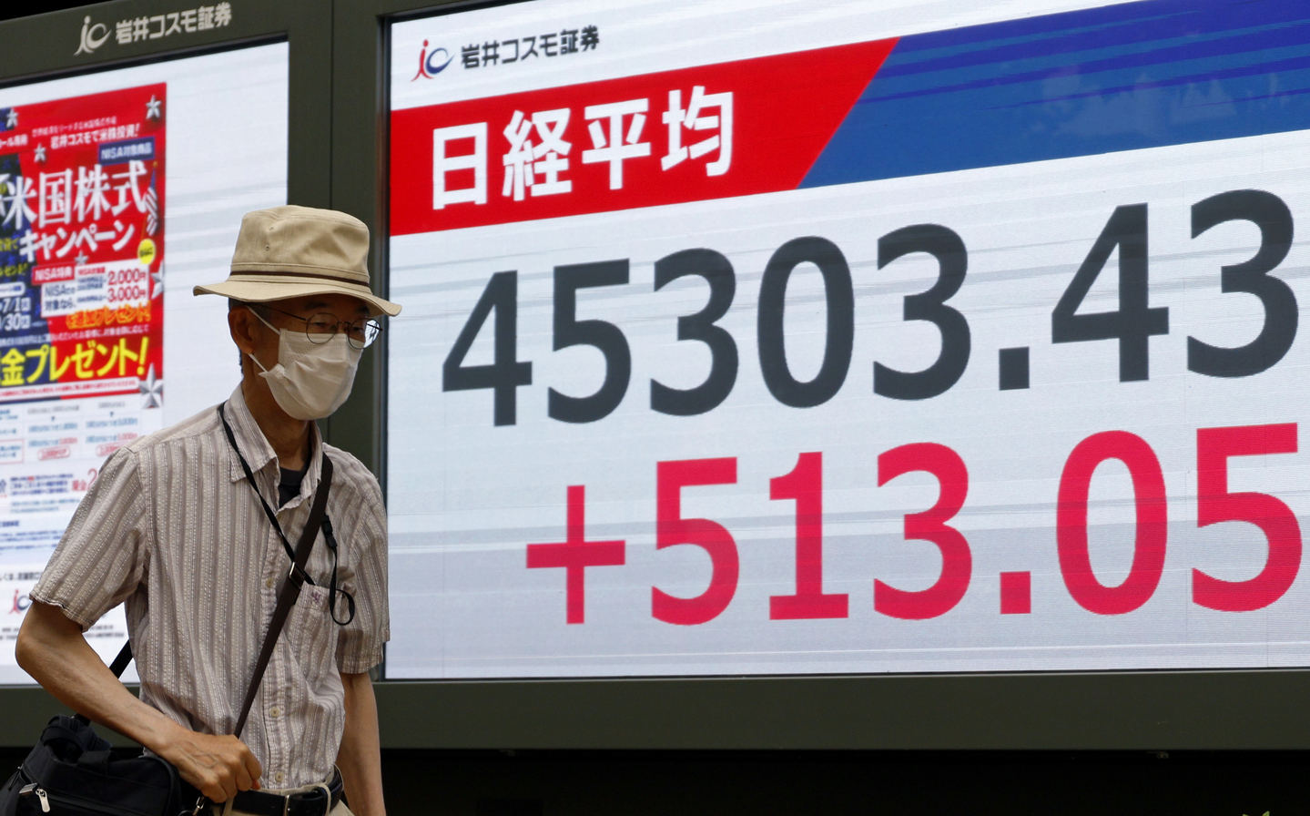 A passerby walks past a stock market indicator board in Tokyo on Sept. 18. The Tokyo stock market soared following the U.S. Federal Reserve's decision to cut interest rates. The Nikkei Stock Average gained 513.05 points to close at 45,303.43, surpassing the 45,000 mark for the first time. [EPA/YONHAP]