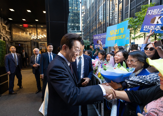 President Lee Jae Myung, left, greets people on the streets holding welcome signs before attending a gathering with the Korean community at a hotel in New York on Sept. 22. [JOINT PRESS CORPS]
