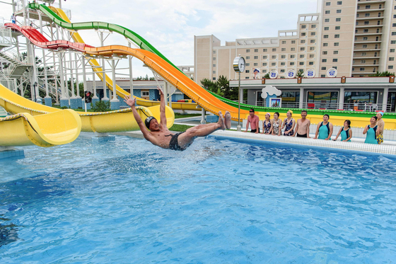 Tourists watch as a man uses a slide into a swimming pool at the Myongsasimni Water Park in the Wonsan Kalma Coastal Tourist Area in Wonsan, North Korea on July 2. [AFP/YONHAP]